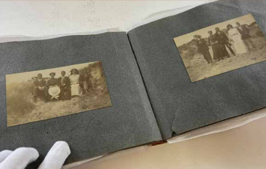 photograph album being held open by a white gloved hand