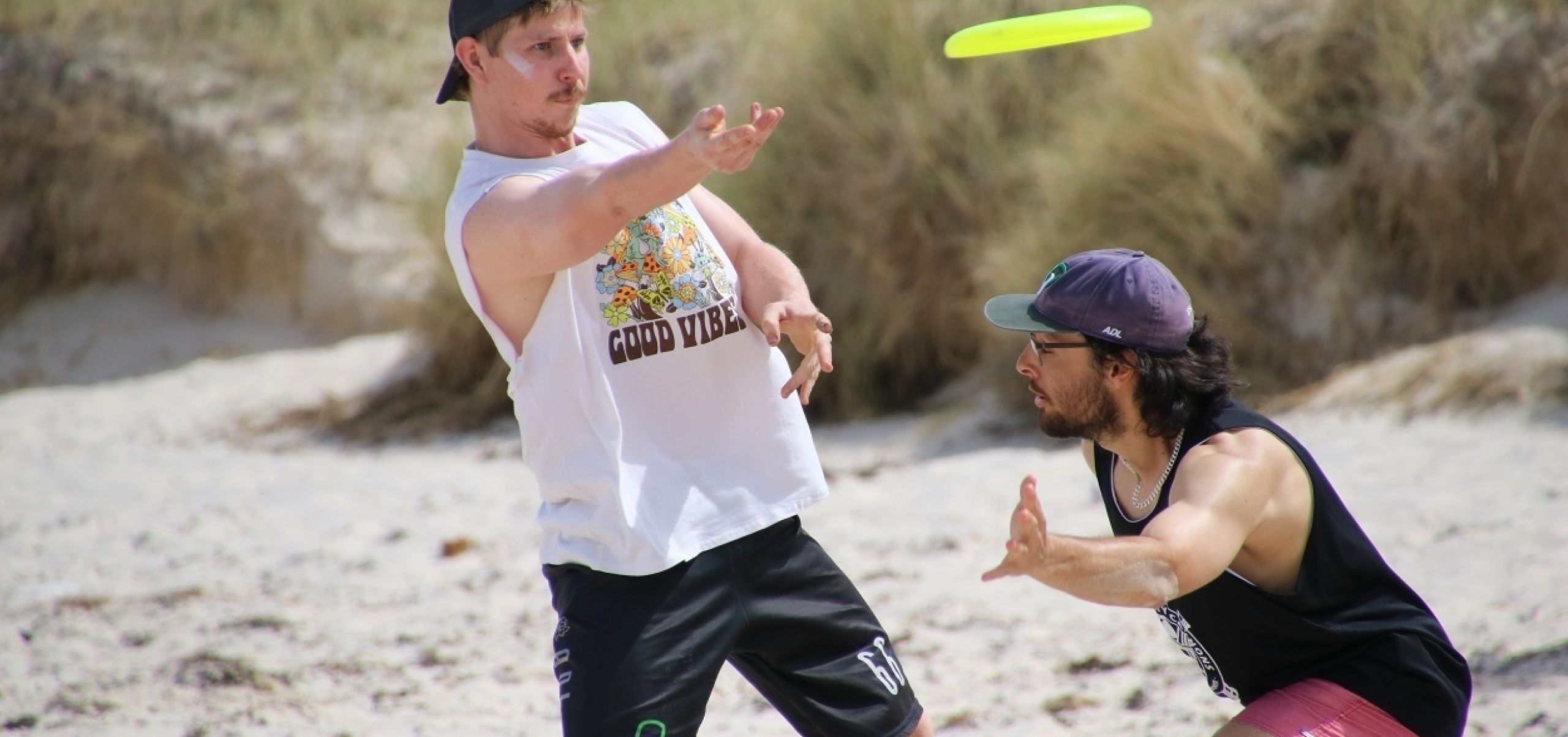 two men playing Frisbee on the beach