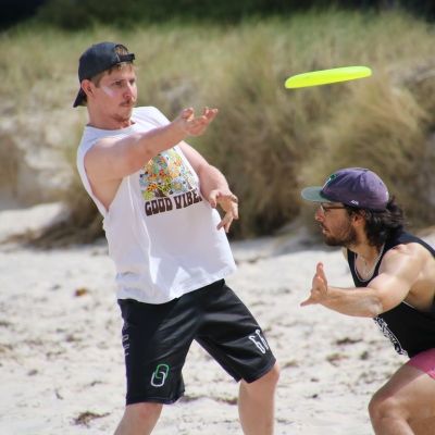 two men playing Frisbee on the beach