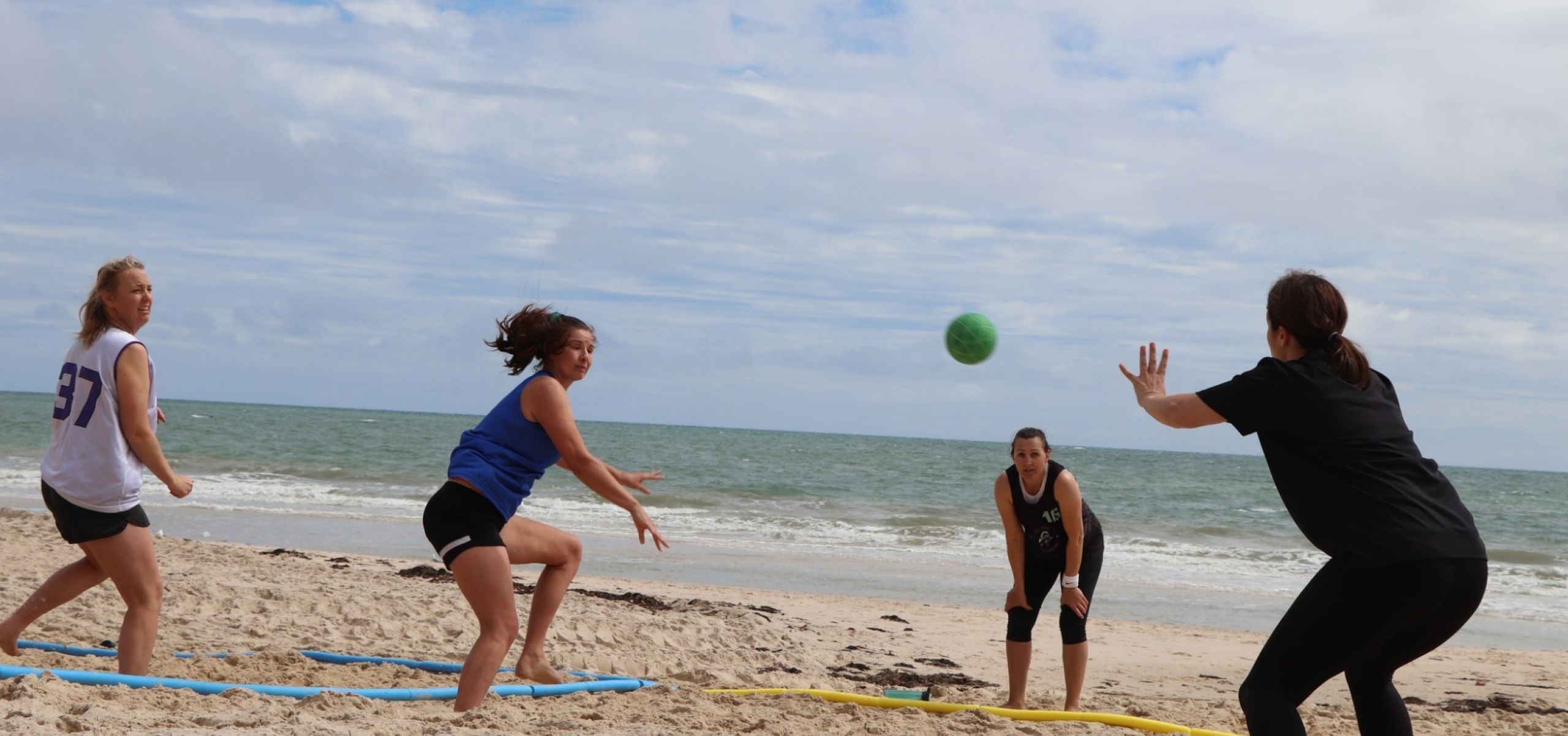 Four people playing handball on the beach