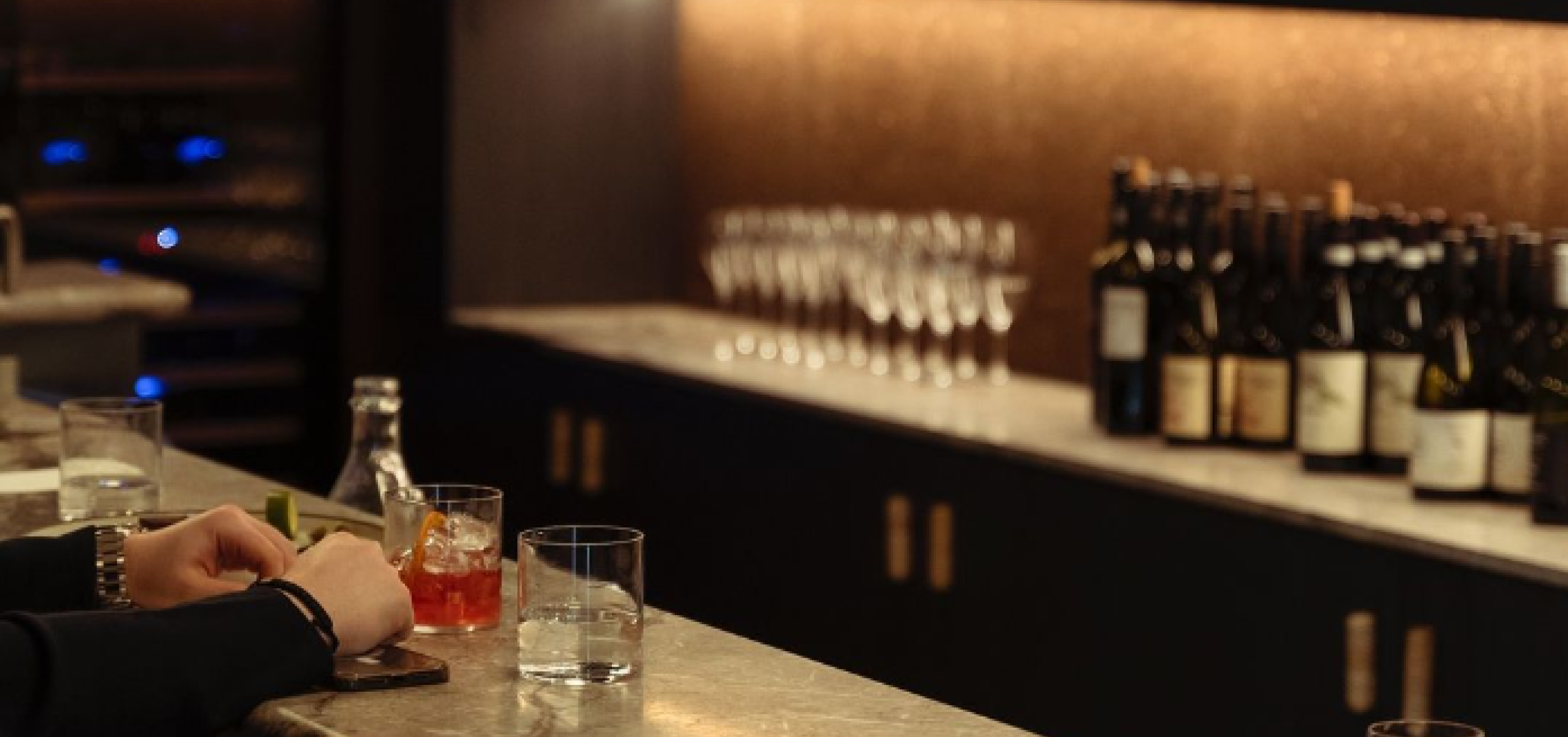 three glasses sitting on bar one half full with pink liquid