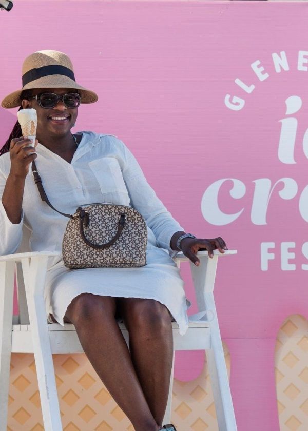lady sitting on high white seat eating ice cream with back of child taking photo