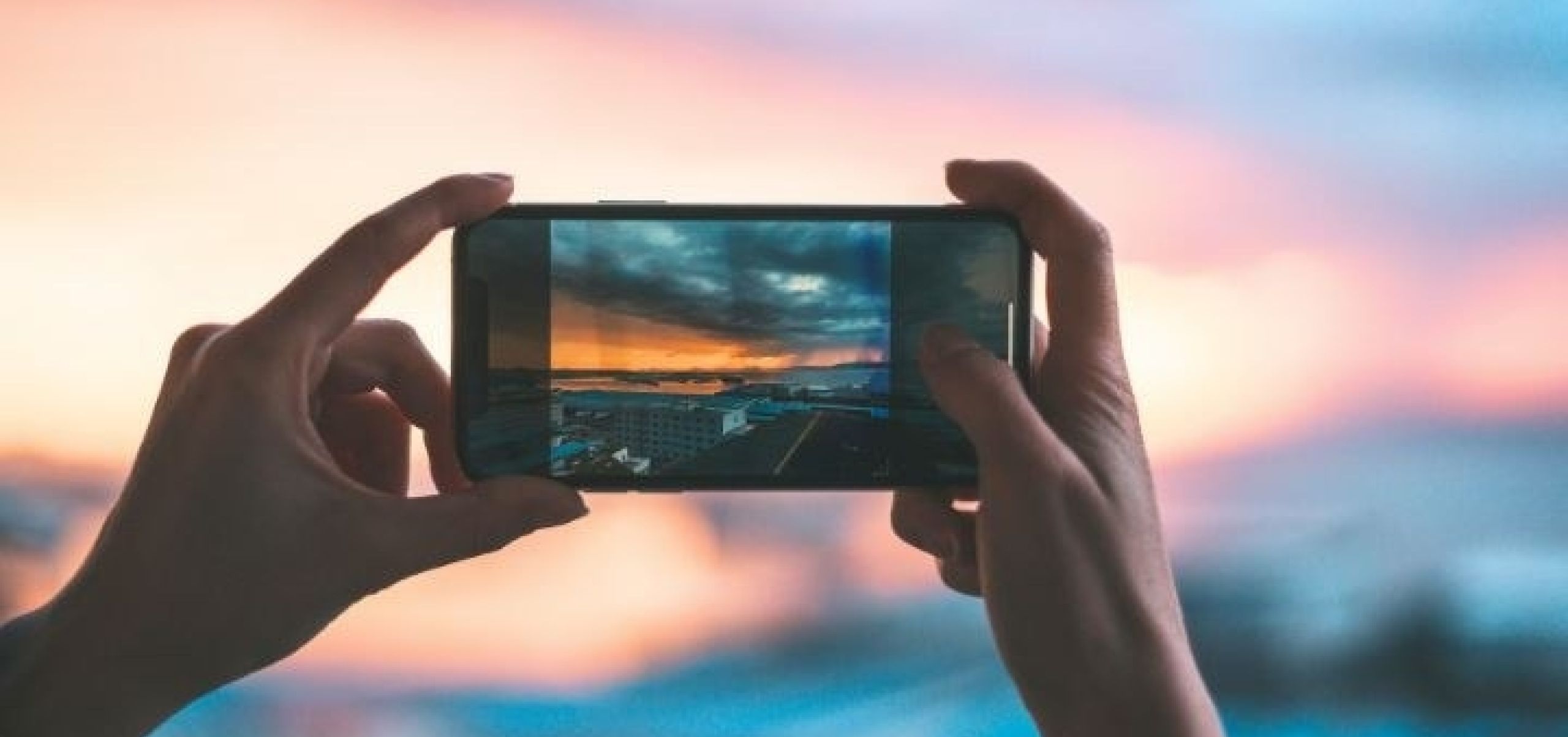 image of someone holding their phone up to capture the sunset