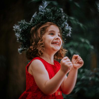 Young girl in a red dress looking excited with a Christmas decorated hat