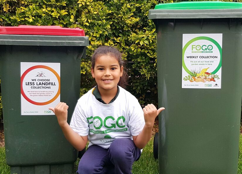 Girl between wheelie bins