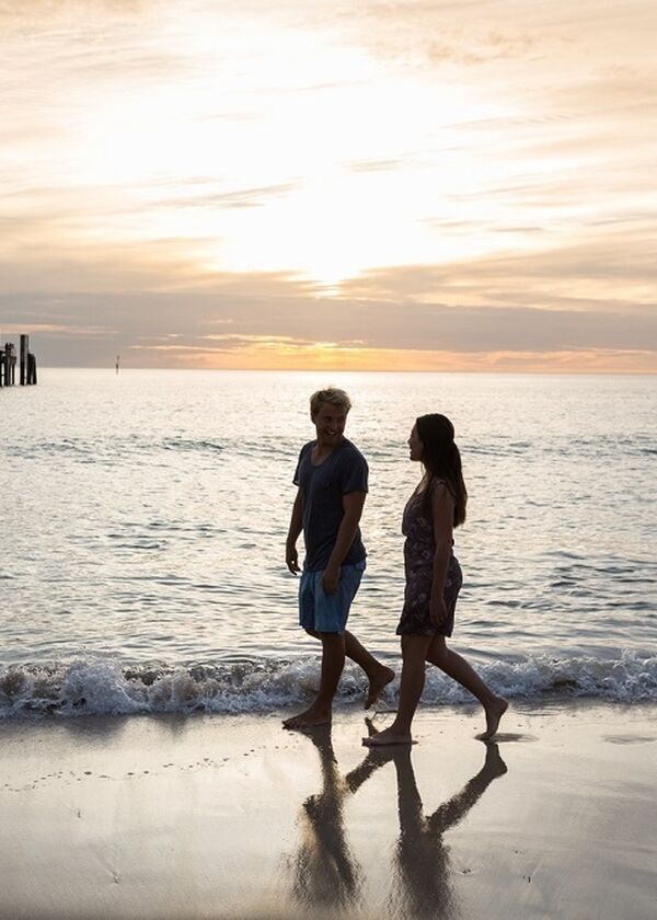 two people walking on glenelg beach at twilight