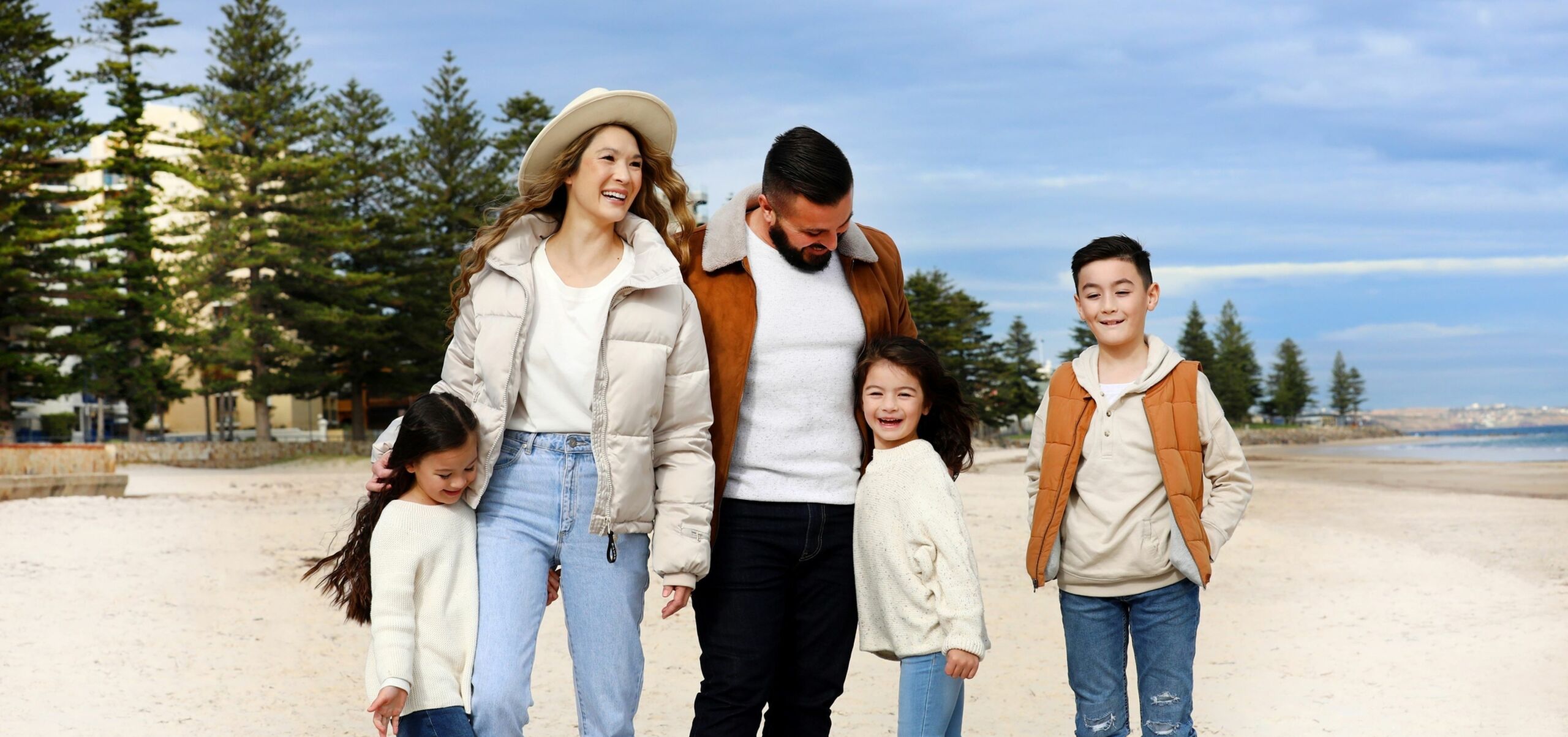 Family with two adults and three children standing on the Glenelg beach