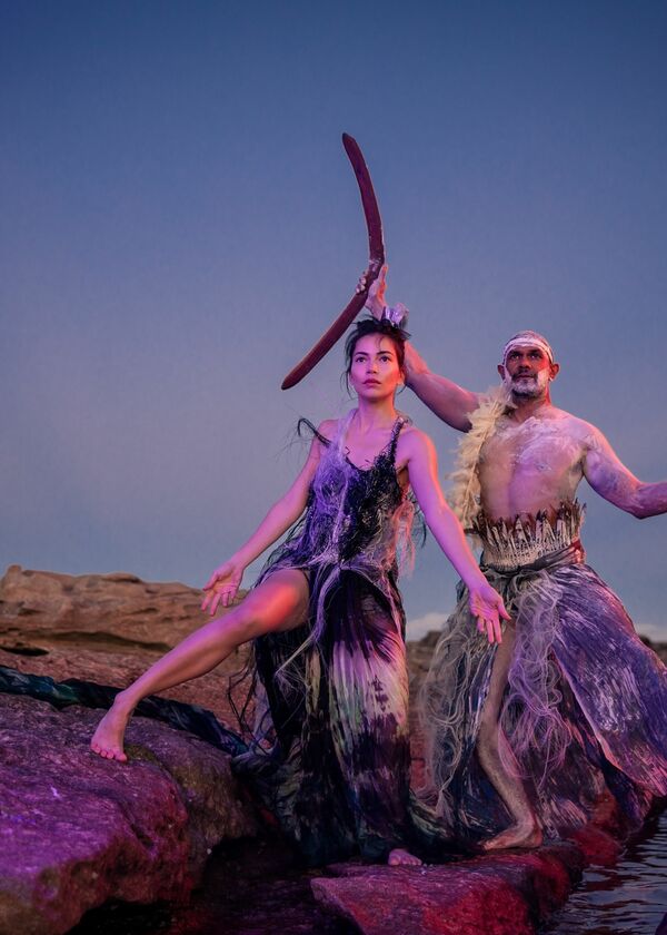 Two dancers posing in front of a purple sunset