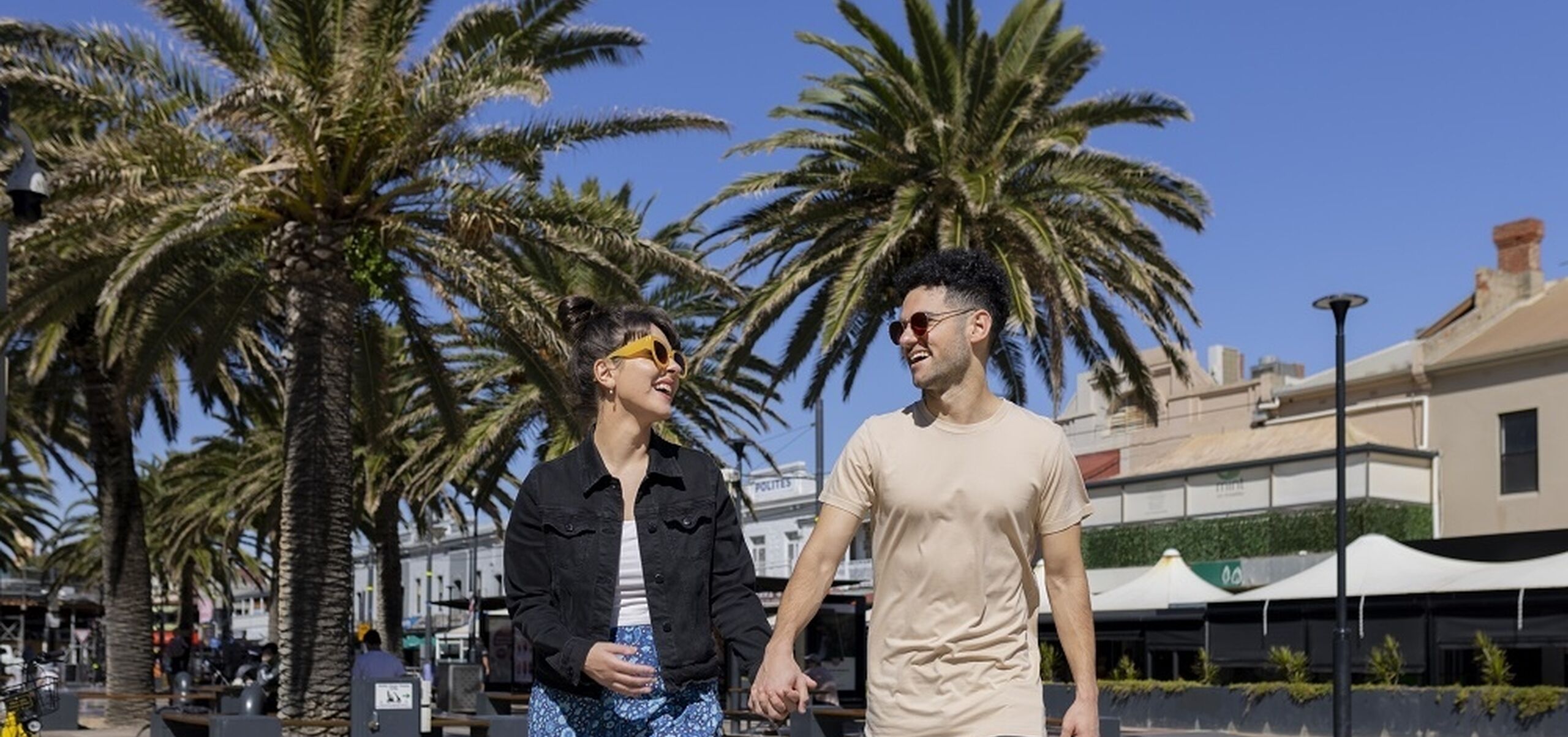 Man and women walking through Moseley Square holding hands looking at each other laughing