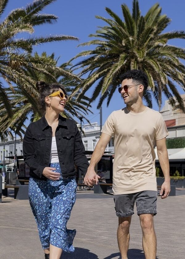 Man and women walking through Moseley Square holding hands looking at each other laughing