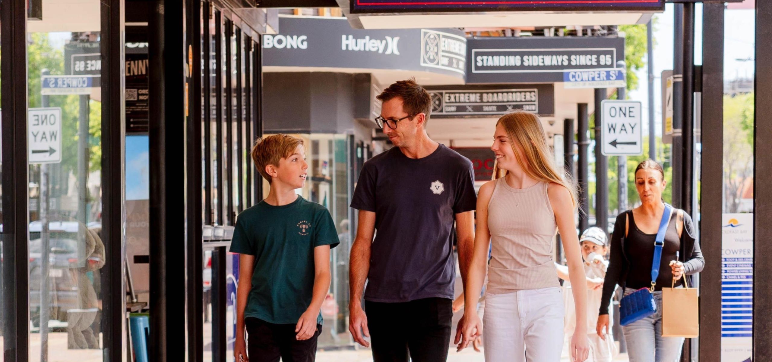Young male, adult male and young female walking under Benny Burgers sign