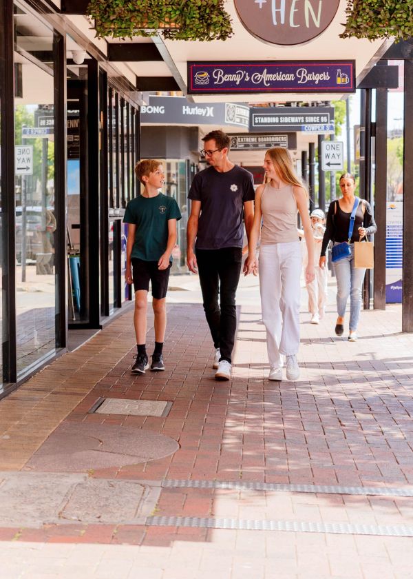 Young male, adult male and young female walking under Benny Burgers sign