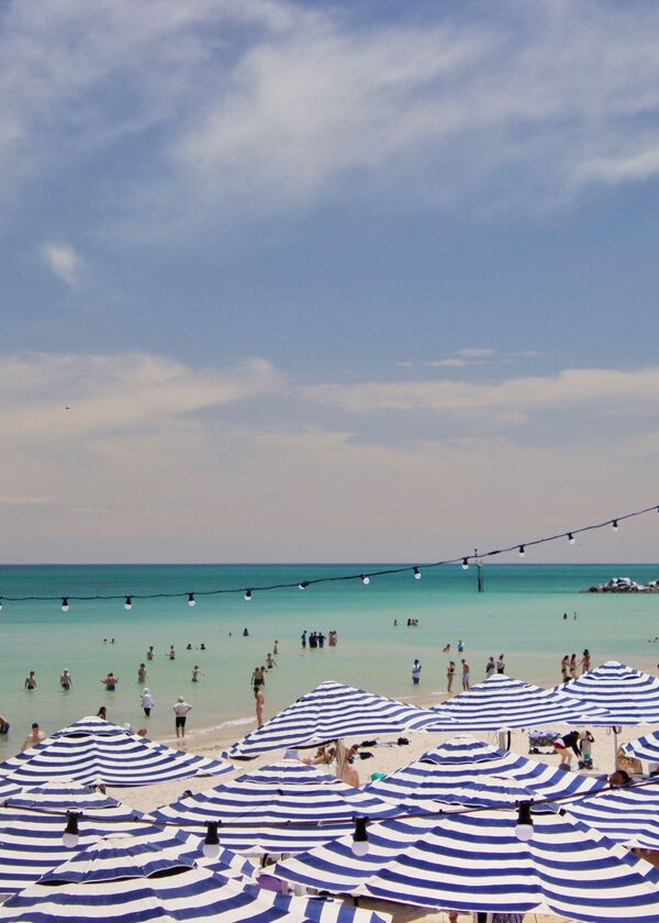 Blue and white umbrellas on the beach with people swimming