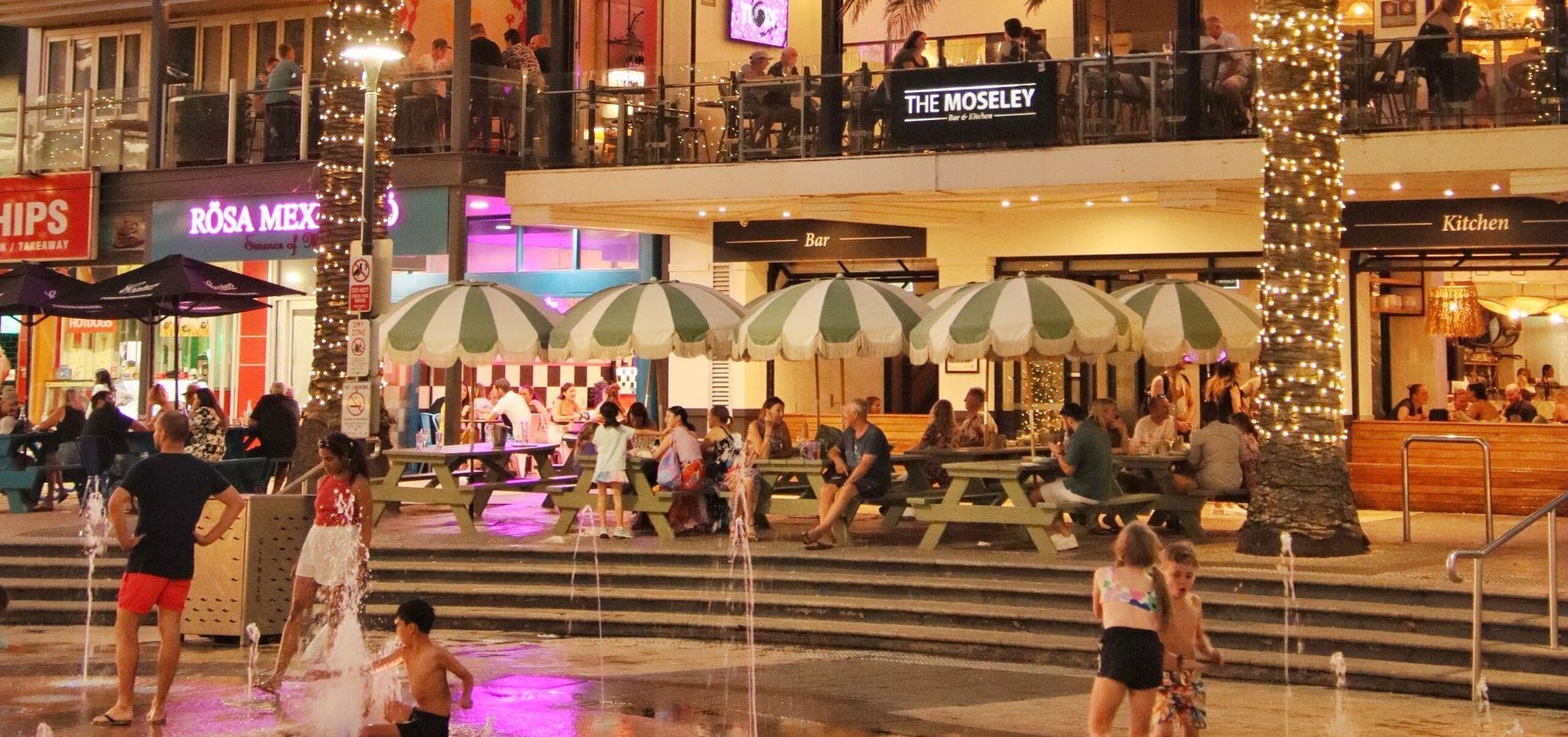 Children playing in water fountain in front of restaurant