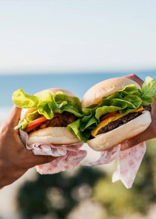 Two hands holding two burgers
