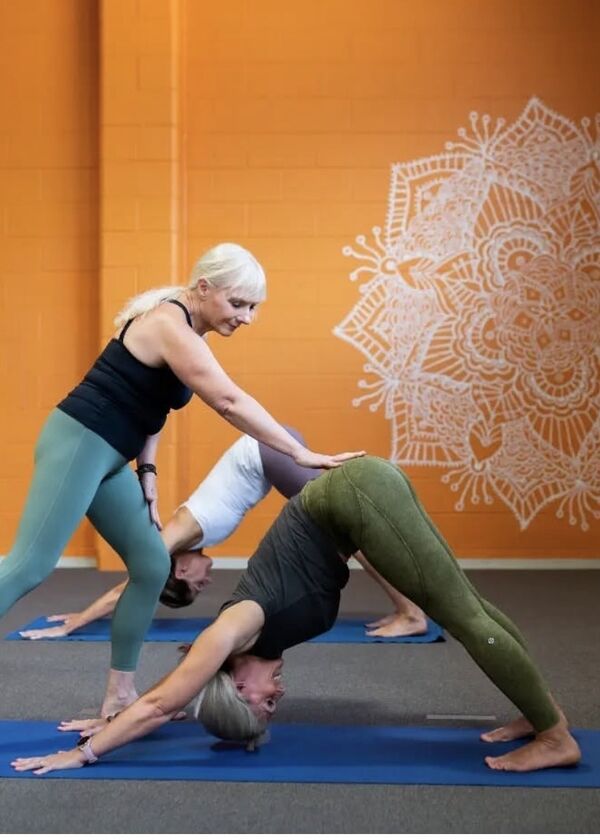 yoga instructor helping someone with downward dog